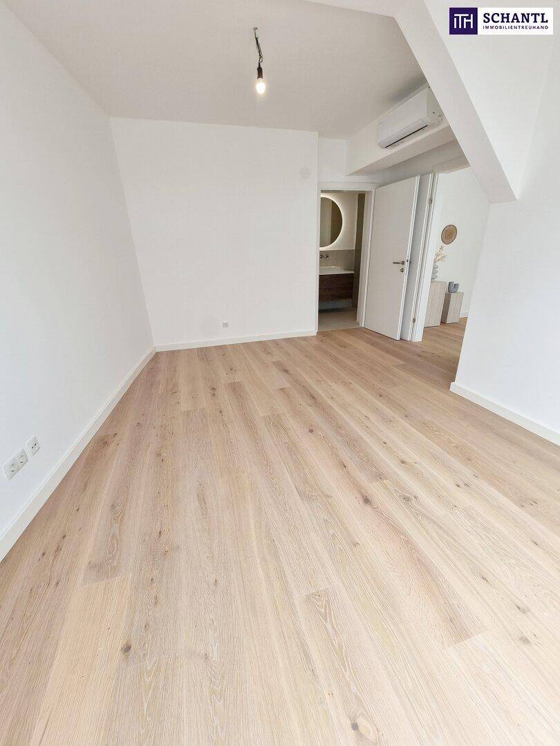 Helles, unmöbliertes Zimmer mit Holzboden, Klimaanlage und Zugang zum Badezimmer.