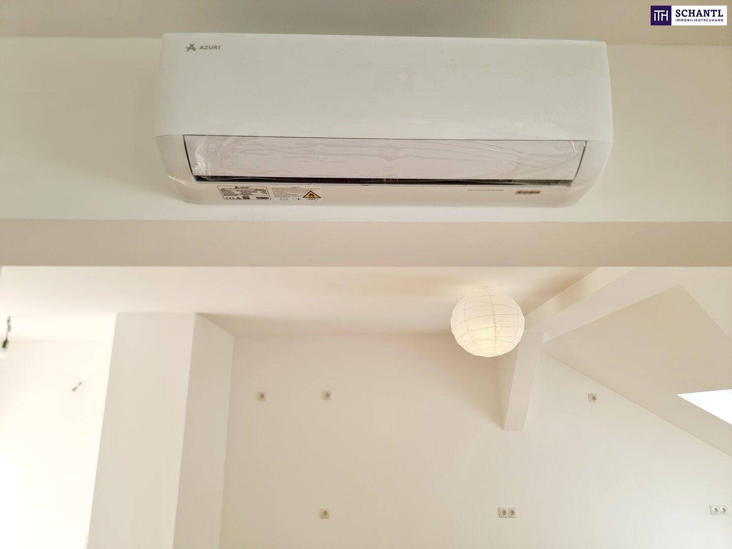Eine moderne Klimaanlage ist an der weißen Wand montiert, mit einer Deckenleuchte darunter.