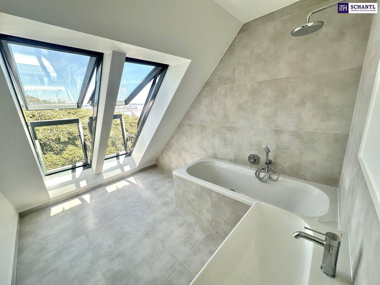 Modernes Badezimmer im Dachgeschoss mit Badewanne, Regendusche und großen Dachfenstern für viel Tageslicht.