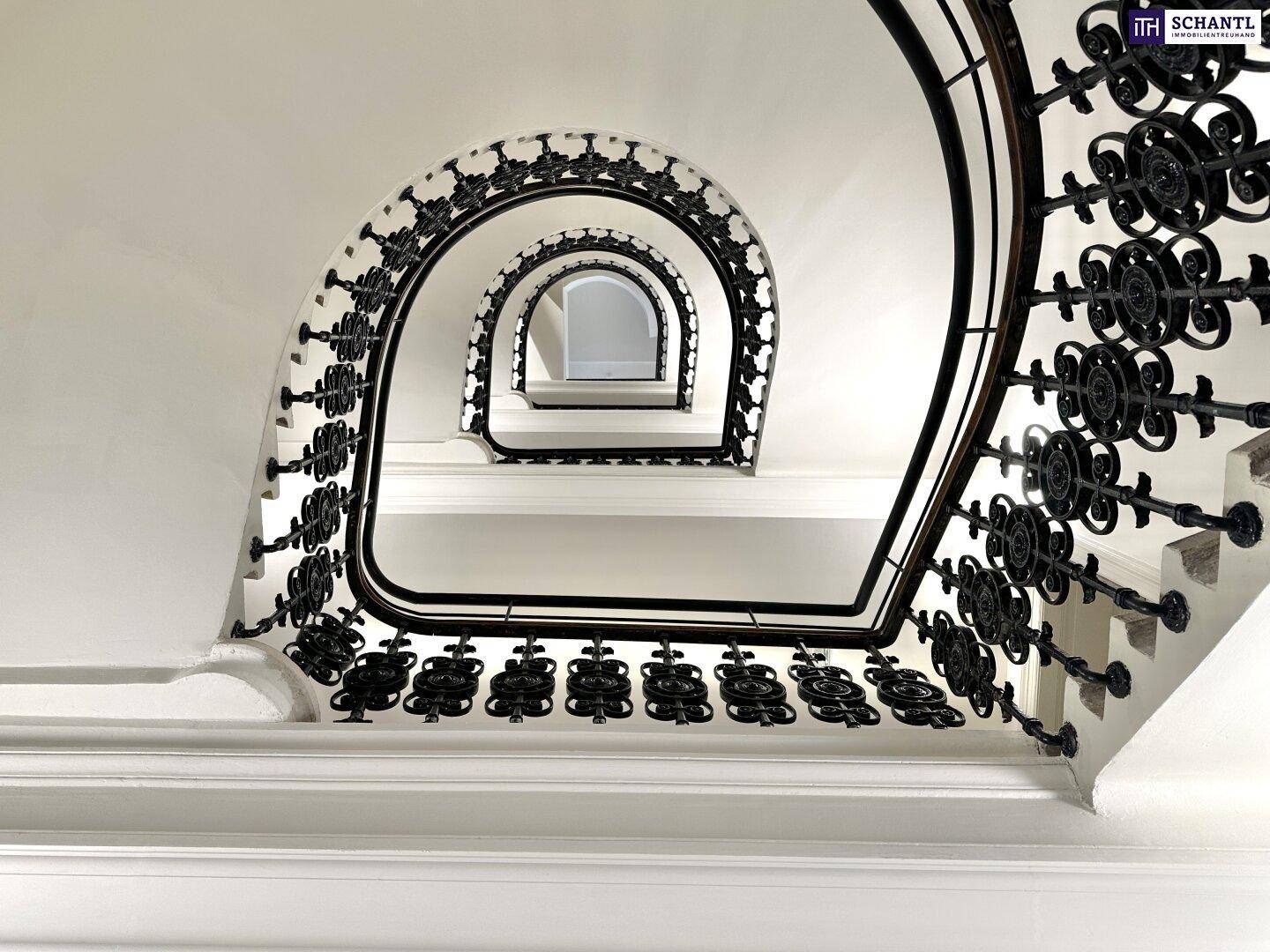Elegantes Treppenhaus mit kunstvollem schmiedeeisernem Geländer und geschwungener Architektur.