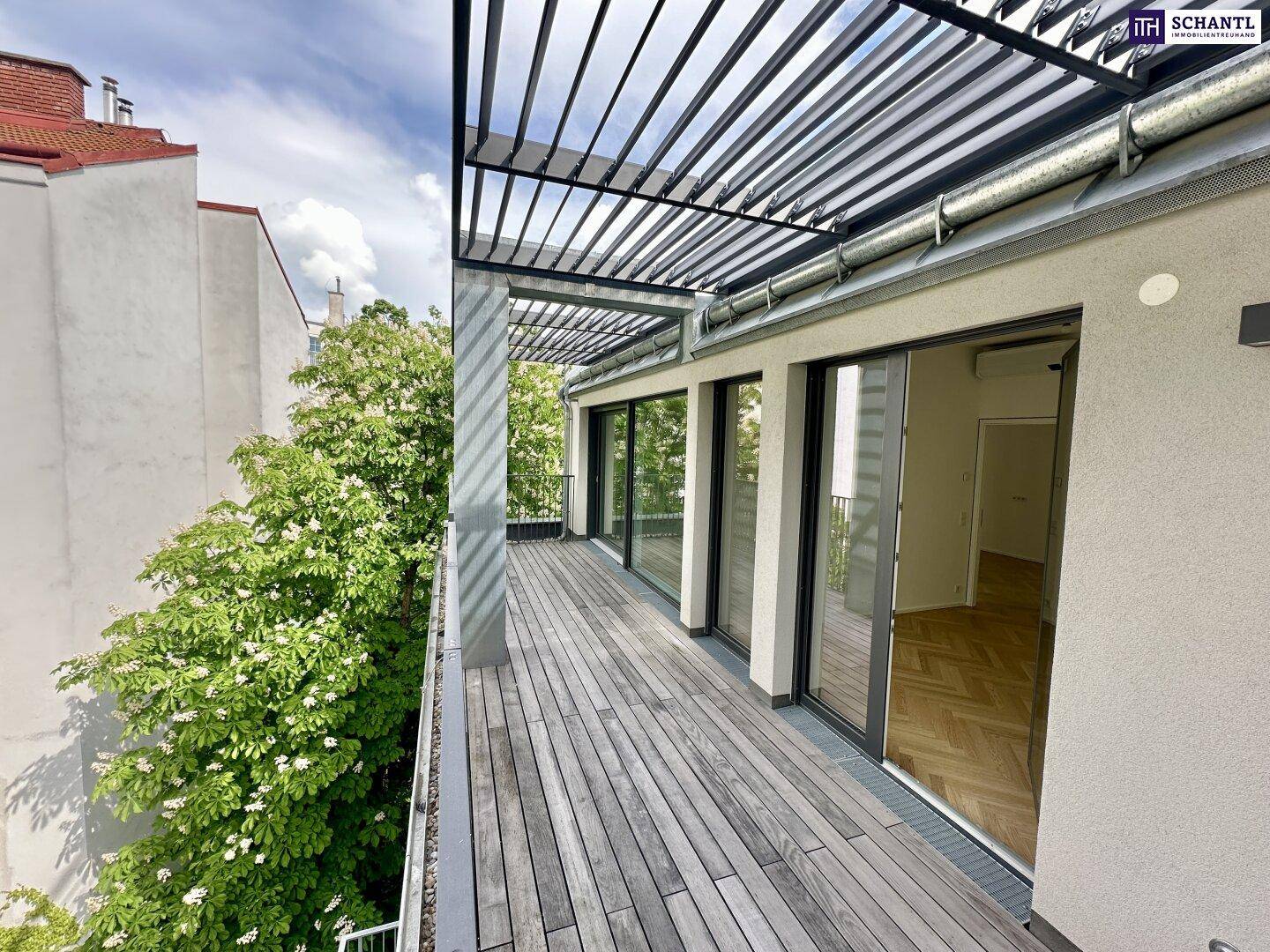 Große Holzterrasse mit Pergola und Blick ins Grüne, ideal für entspannte Stunden im Freien.