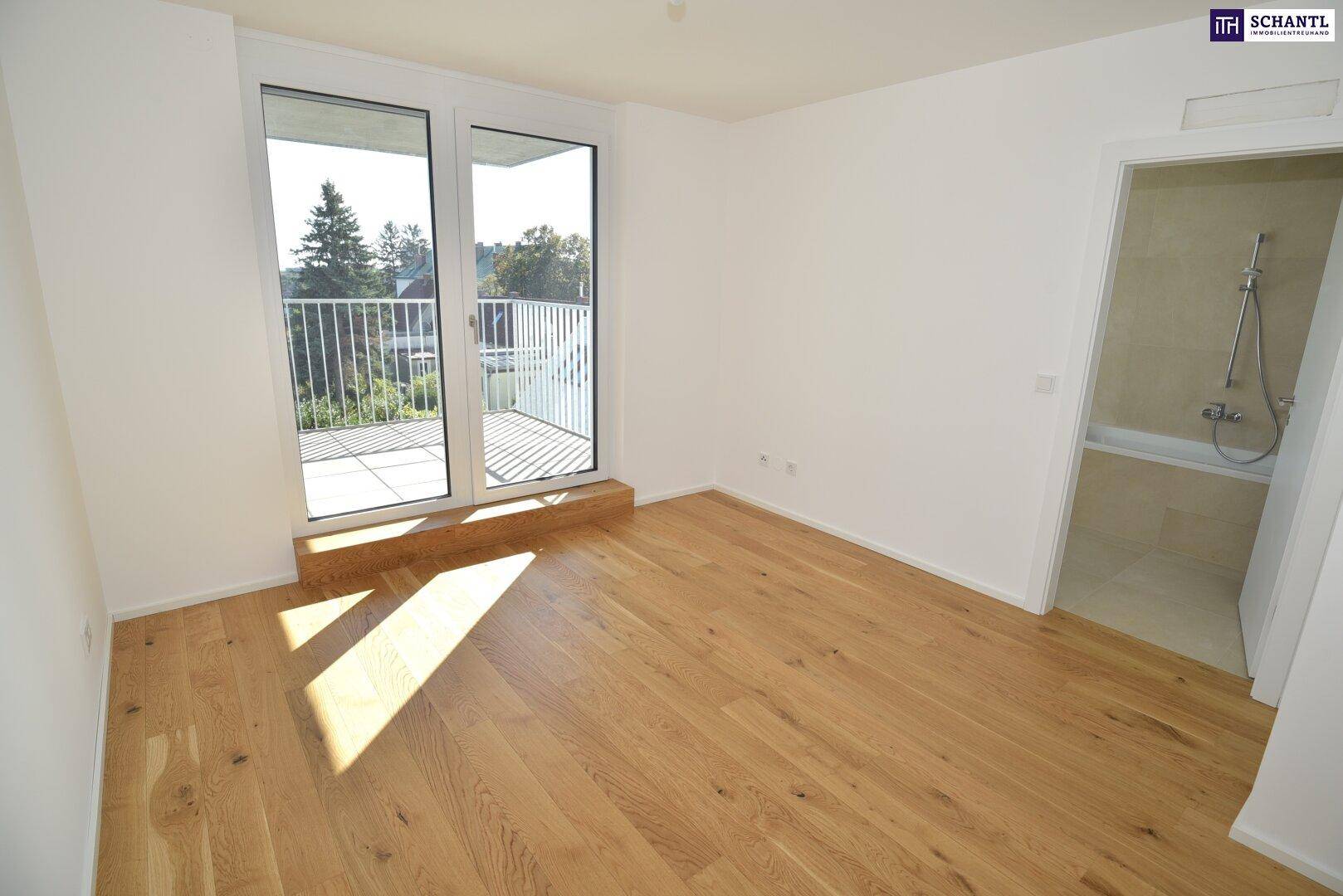 Helles Schlafzimmer mit Holzboden und Zugang zu einem Balkon, daneben ein Badezimmer.