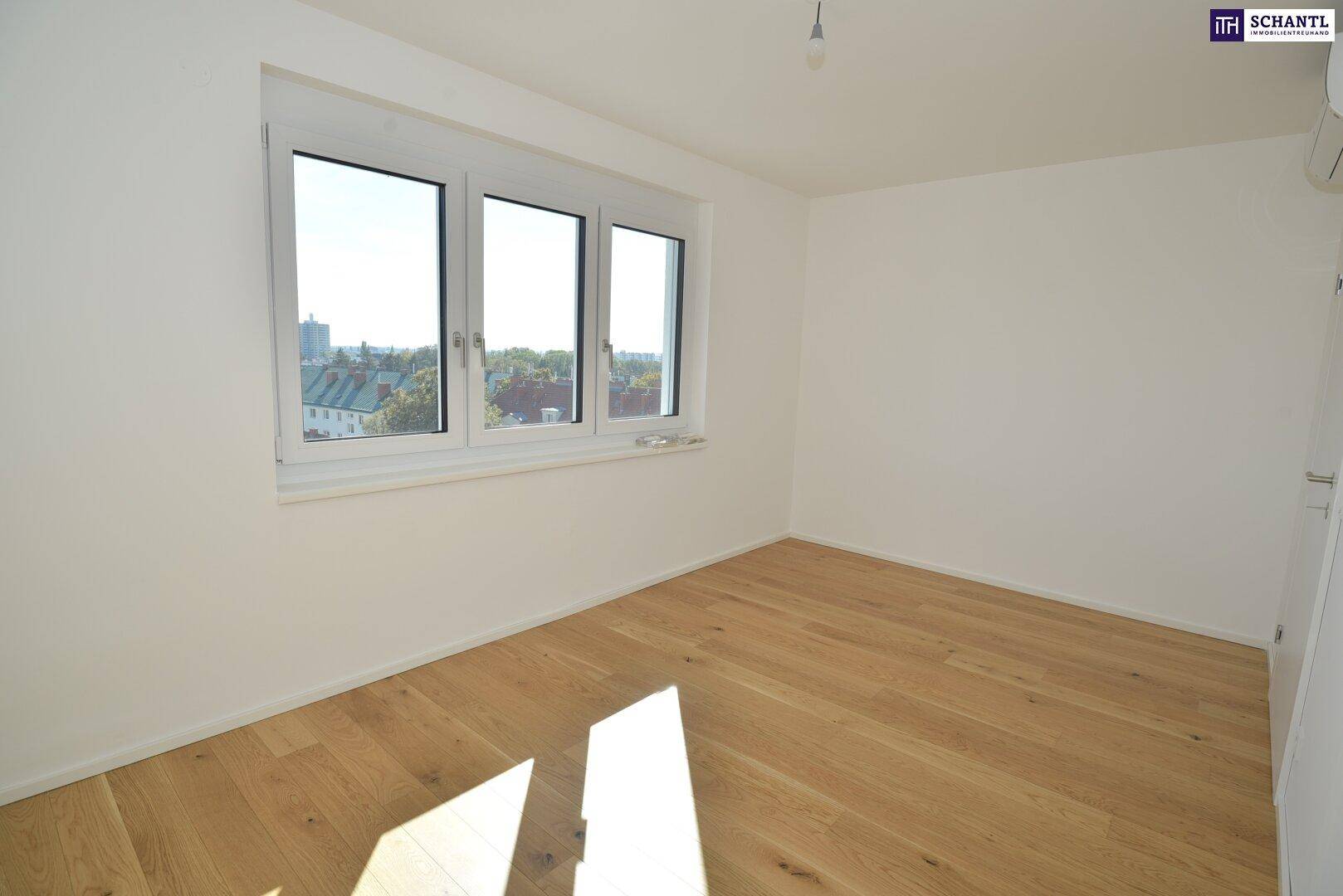 Helles Schlafzimmer mit Holzboden und einem großen Fenster, das einen Blick auf die Stadt bietet.