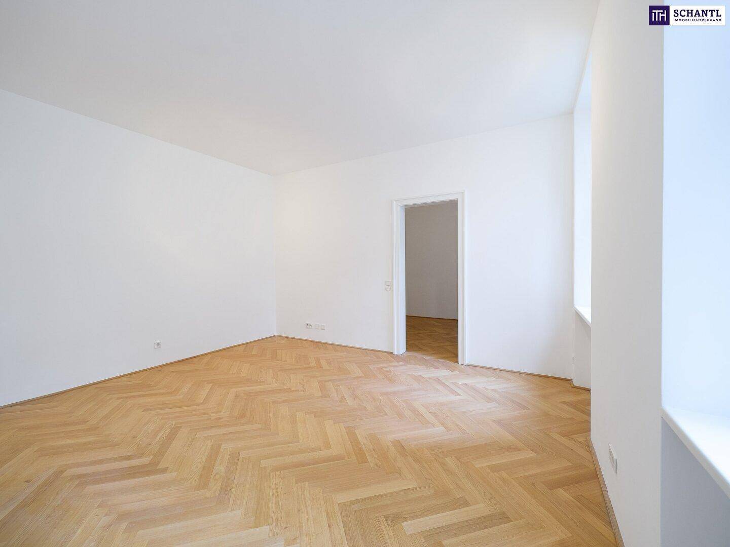 Heller, leerer Raum mit elegantem Fischgrätparkett und frisch gestrichenen weißen Wänden.