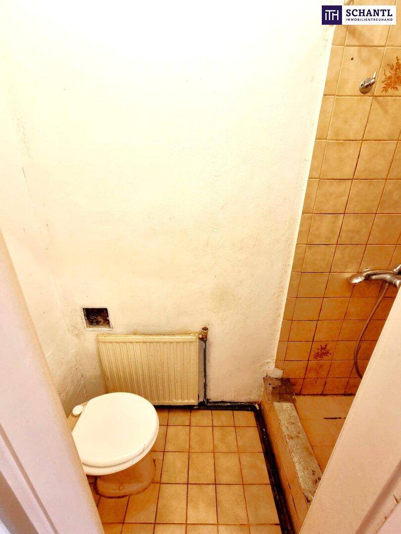 Kleines WC mit Toilette und Heizkörper, ausgestattet mit einfachen Fliesen.