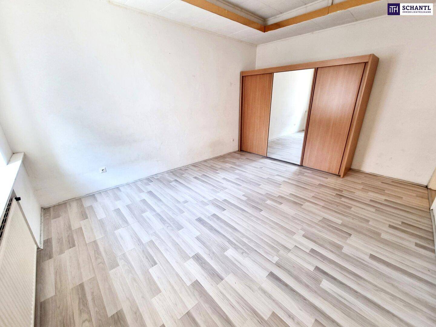 Helles Zimmer mit Laminatboden und großem Spiegelschrank, bereit zur individuellen Gestaltung.