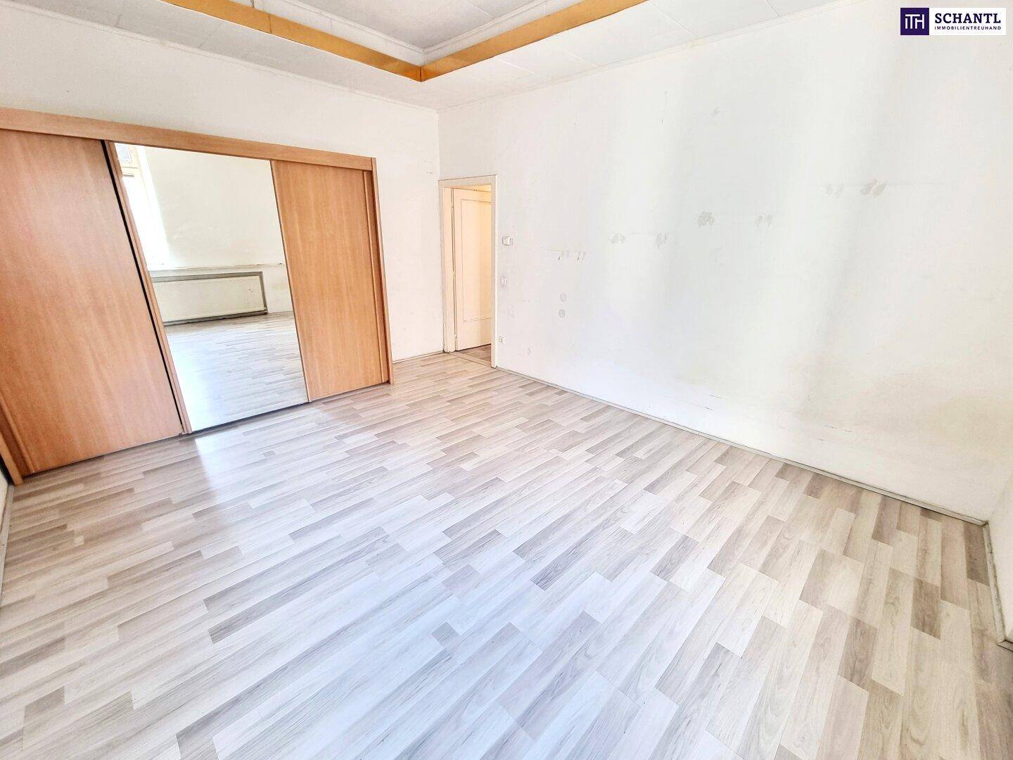 Geräumiges Zimmer mit Laminatboden und großem Spiegelschrank, ideal als Schlafzimmer.