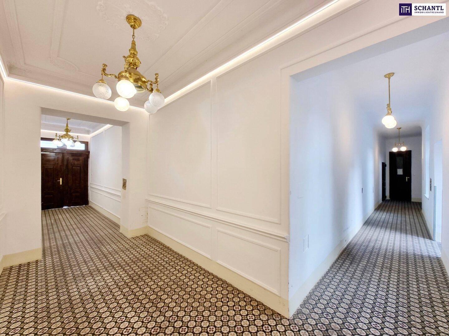 Langer Flur mit historischen Fliesen, Stuckelementen und traditioneller Deckenbeleuchtung, typisch Altbau.