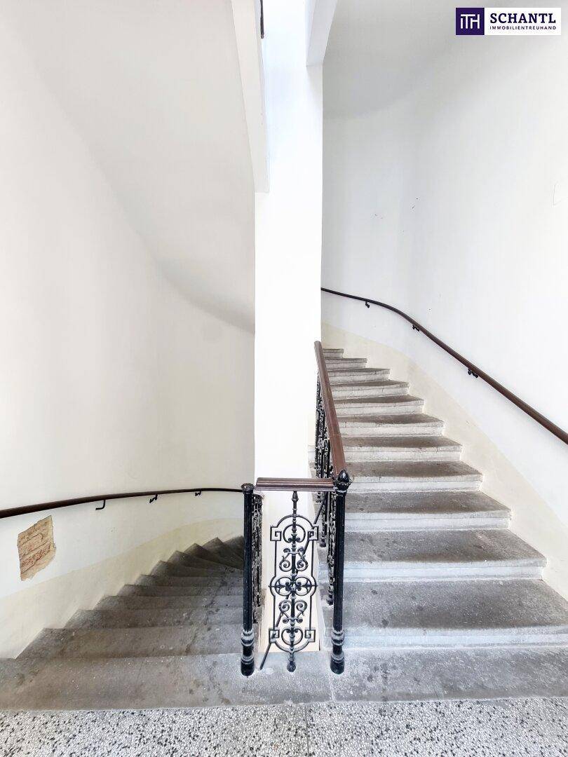 Historisches Treppenhaus mit Steinstufen, schmiedeeisernem Geländer und natürlichem Licht von oben.