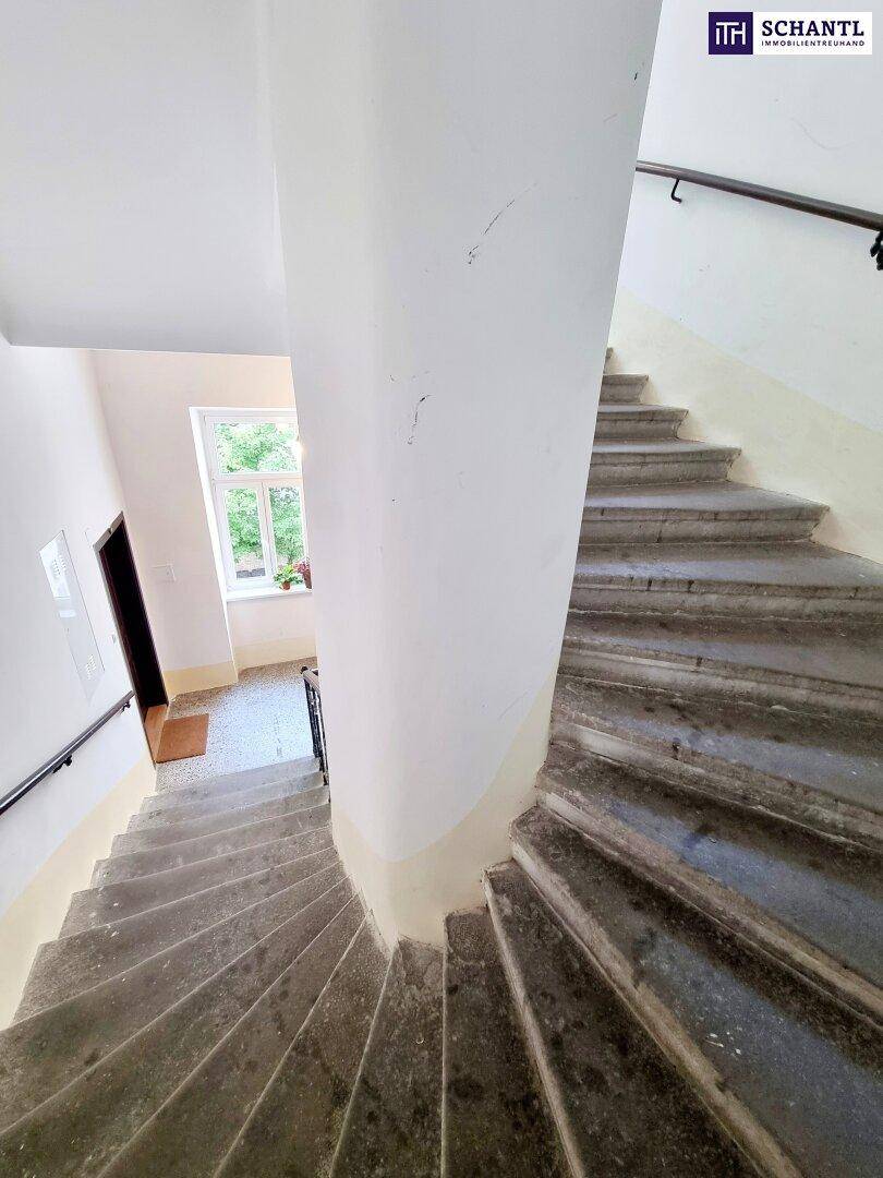 Historisches Treppenhaus mit Steinstufen, schmiedeeisernem Geländer und natürlichem Licht von oben.