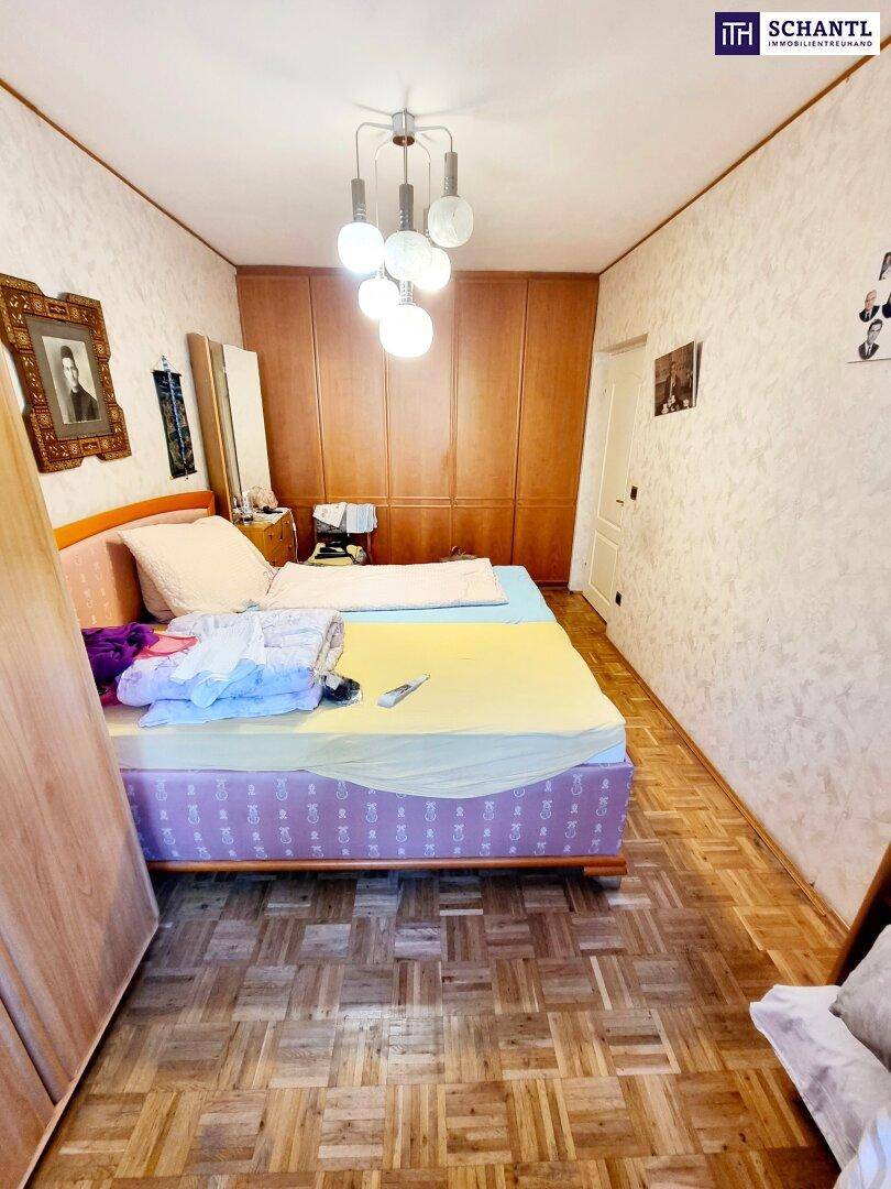 Schlafzimmer mit Parkettboden, Einbauschränken und schlichter, funktionaler Einrichtung.