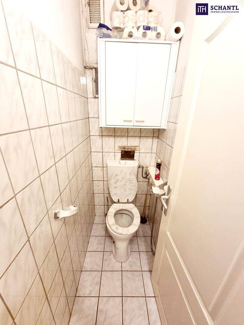 Kleines WC mit Fliesen an Wänden und Boden sowie einem praktischen Hängeschrank.