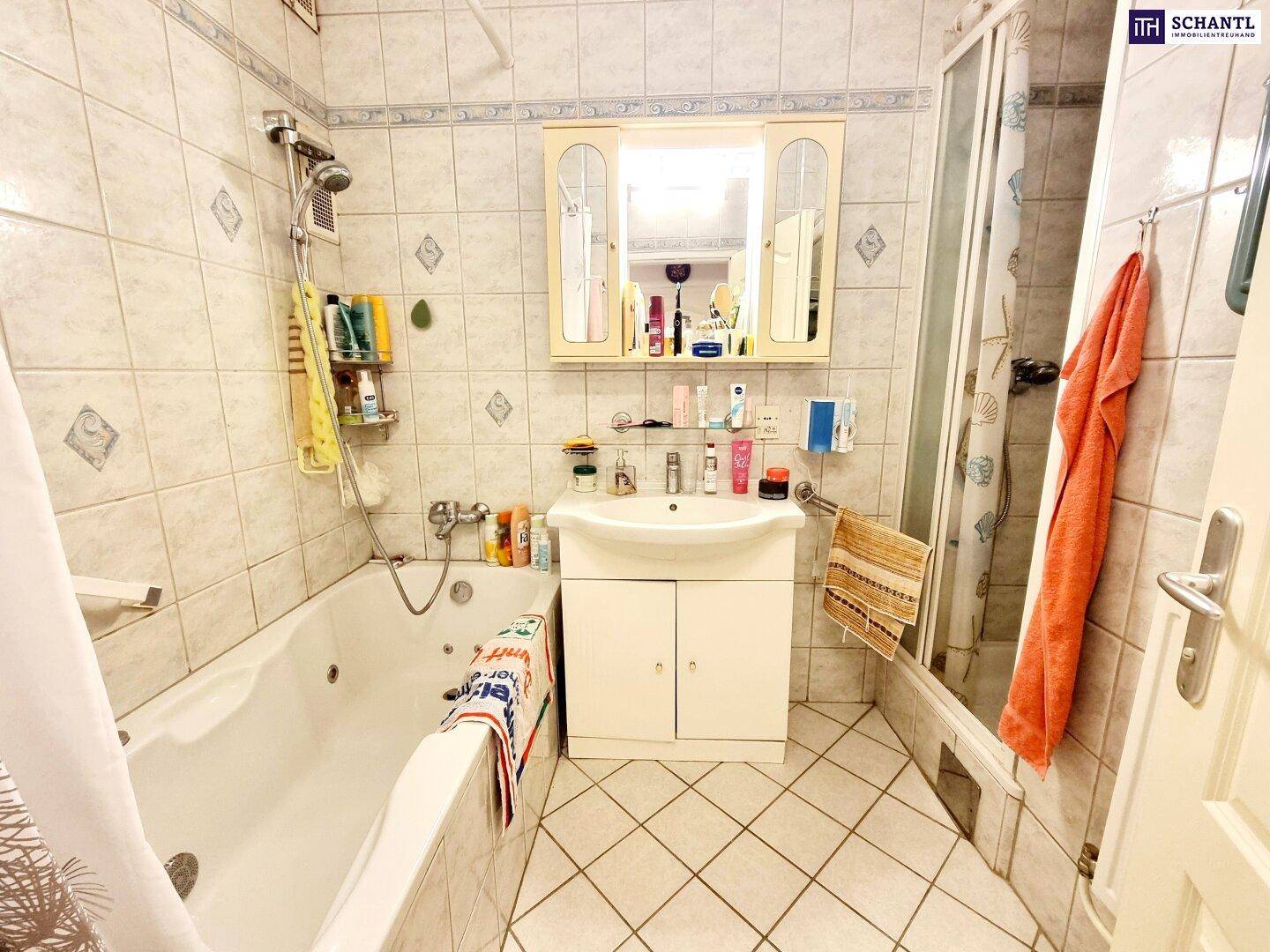 Badezimmer mit Badewanne, Duschkabine, Waschbecken und hellen Wandfliesen.