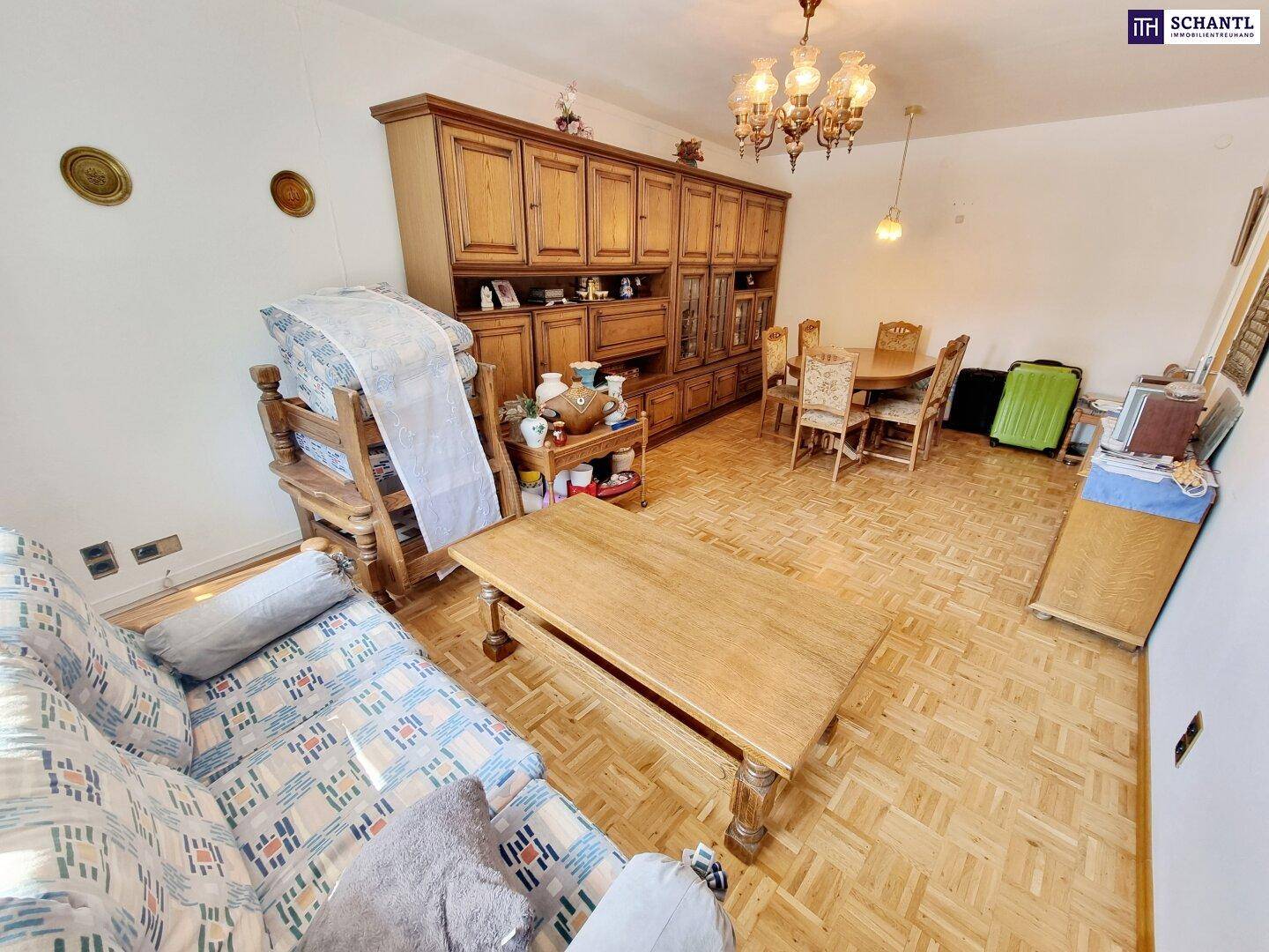 Geräumiger Wohn- und Essbereich mit Parkettboden und traditionellen Holzschränken.