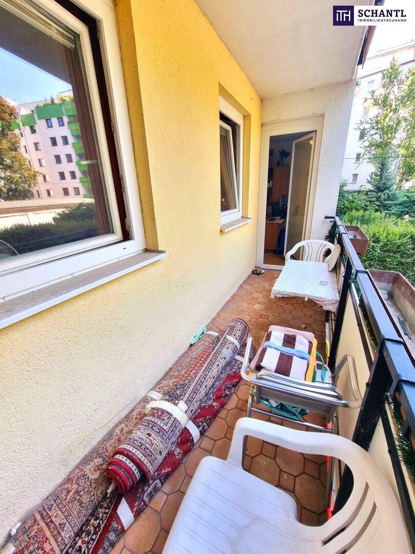 Schmaler Balkon mit Fliesenboden, gelber Fassade und einem angenehmen Blick ins Grüne.
