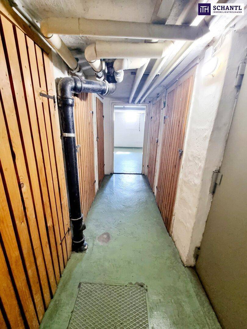Kellerflur mit Holzverschlägen und sichtbaren Rohren an der Decke, bietet Stauraum.