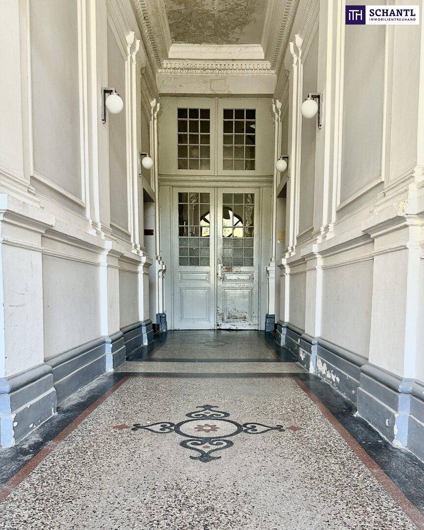 Historischer Eingangsbereich mit Terrazzoboden und hohen Decken.