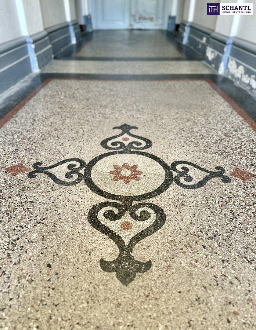 Detailaufnahme des kunstvollen Terrazzobodens im Eingangsbereich des Gebäudes.