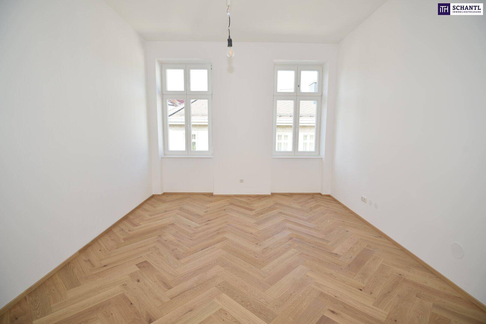 Leeres Zimmer mit frisch verlegtem Fischgrätparkett und weiß gestrichenen Wänden.