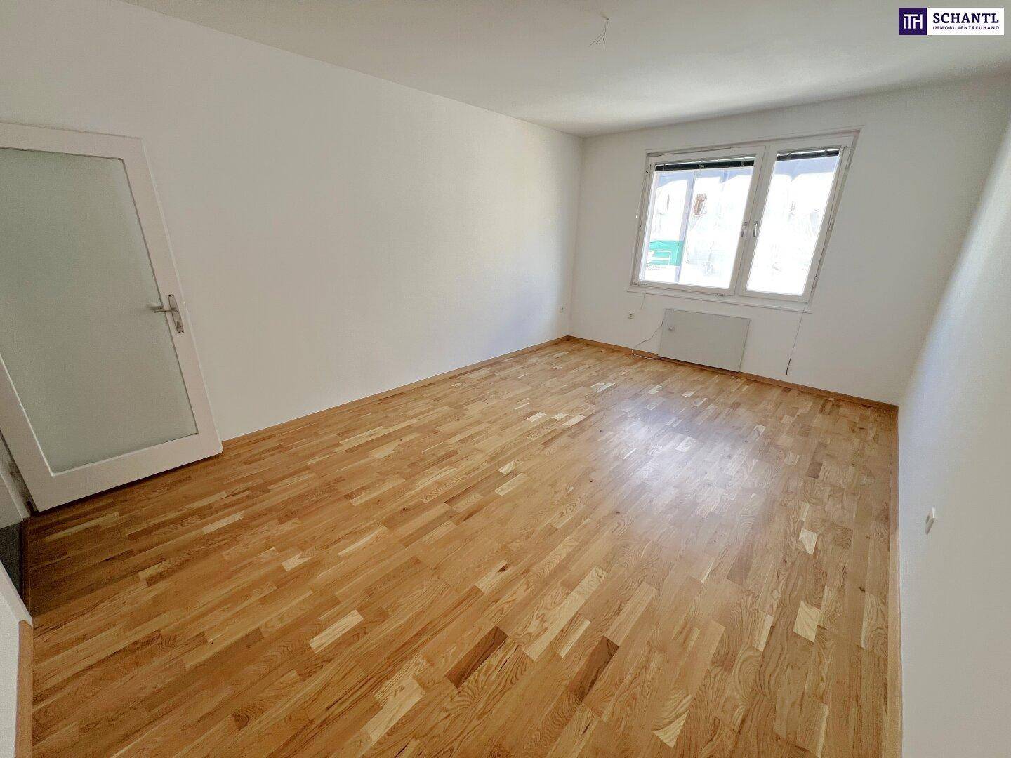 Geräumiges Zimmer mit Parkettboden und einer Tür mit Glaseinsatz, hell und einladend.