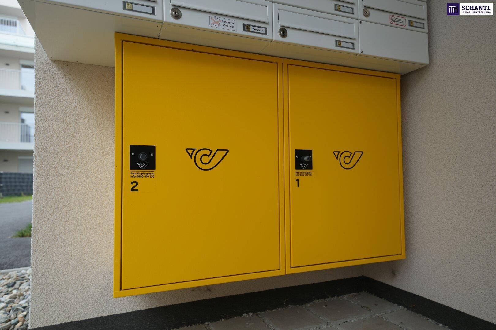 Gelbe Postkästen an der Außenwand eines modernen Wohngebäudes.