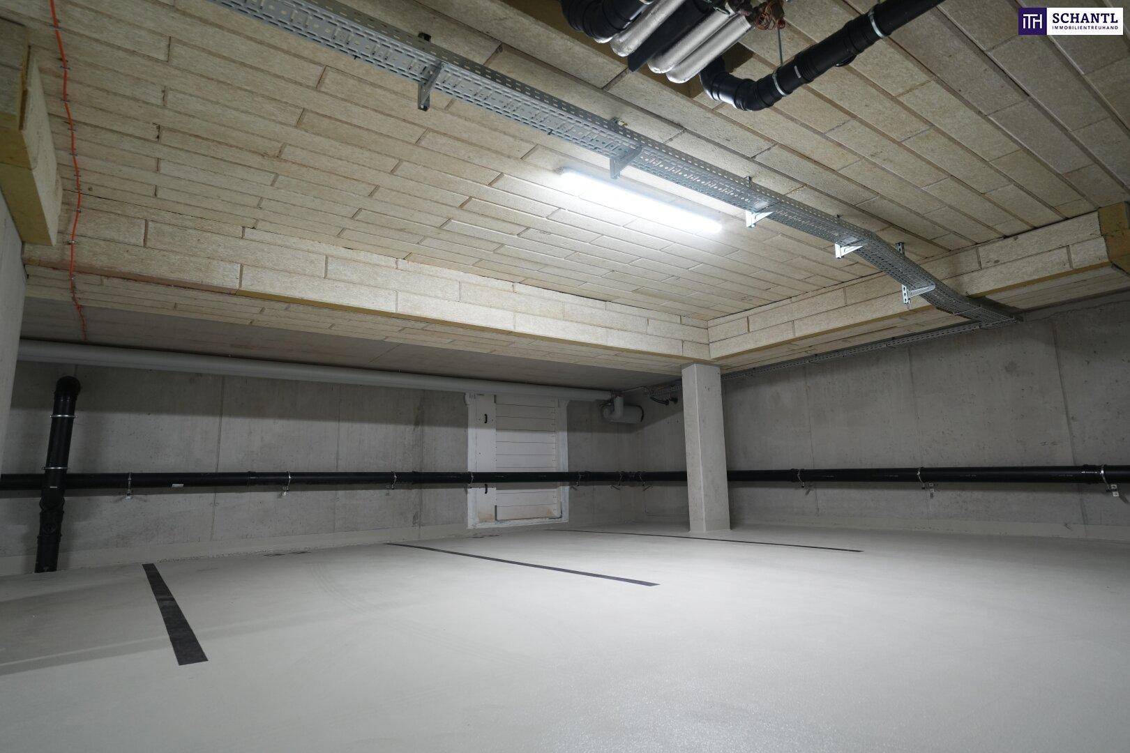 Heller Bereich in der Tiefgarage mit markierten Parkplätzen und sichtbaren Installationen an der Decke.