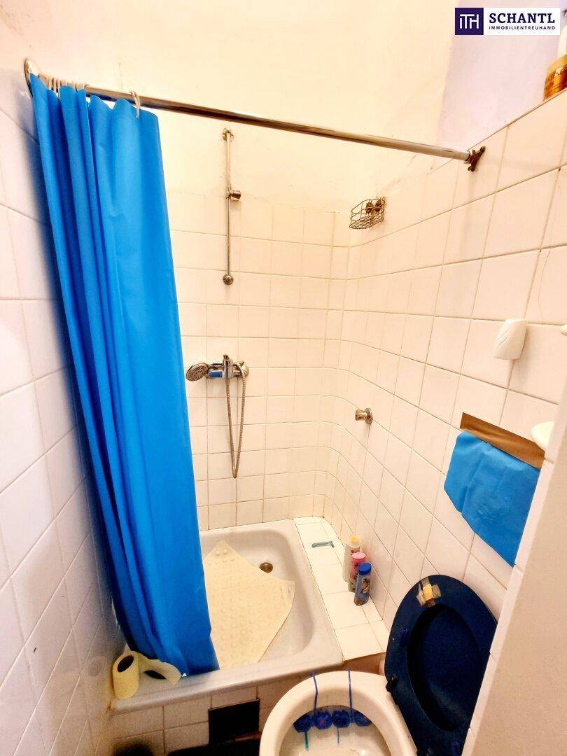 Kleines Badezimmer mit Badewanne, Duschvorhang und Wandfliesen im Stil der 80er Jahre.