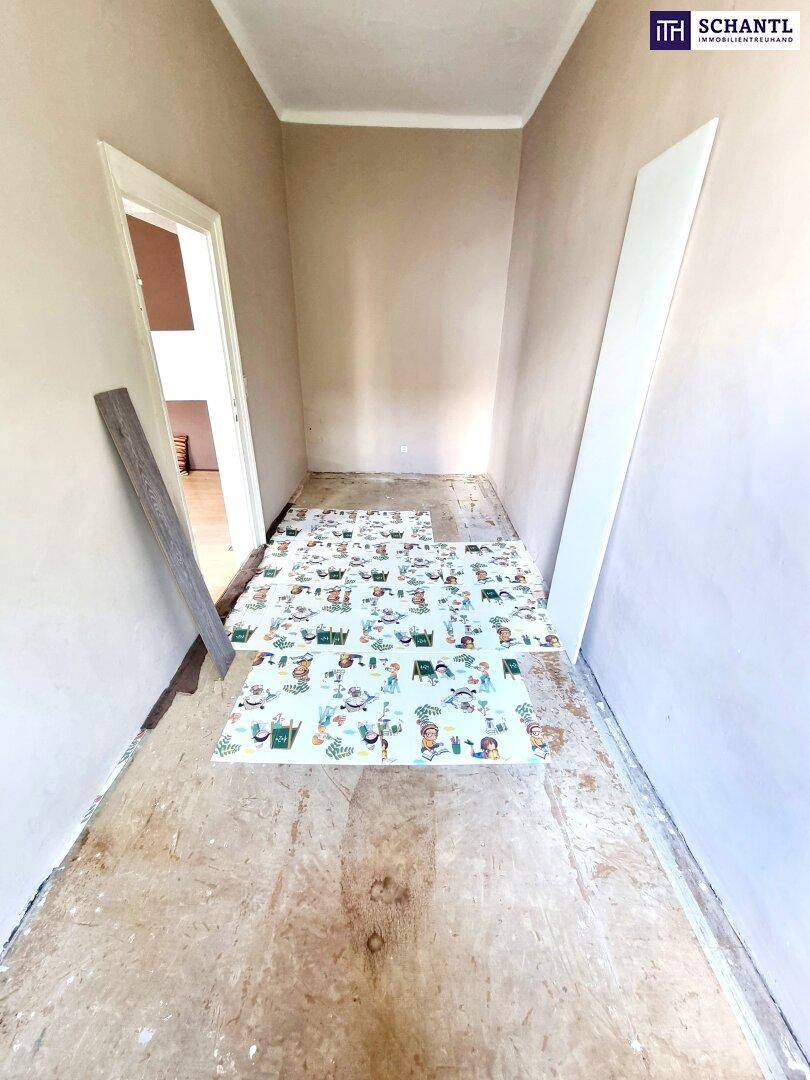 Langer Flur mit freigelegtem Unterboden und Materialien, die auf eine bevorstehende Renovierung hinweisen.