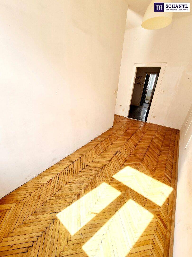 Heller Flur mit Fischgrätparkettboden und Sonnenlicht, das durch eine Türöffnung fällt.