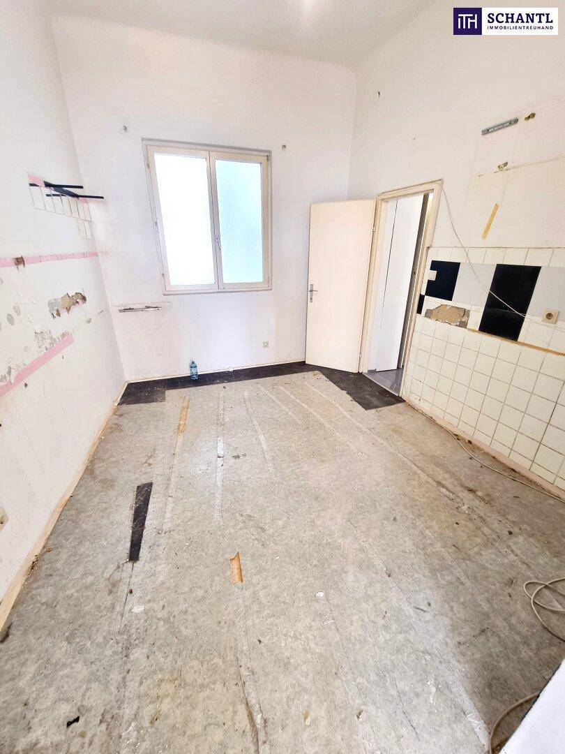 Leere Küche mit Fenster und alten Wandfliesen, bereit für eine Neugestaltung.