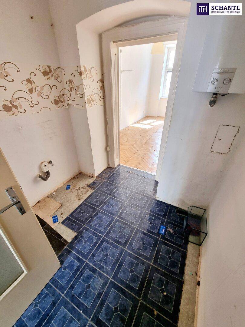 Kleiner WC-Raum mit blauen Fliesen und einer Tür, die zu einem anderen Zimmer führt.
