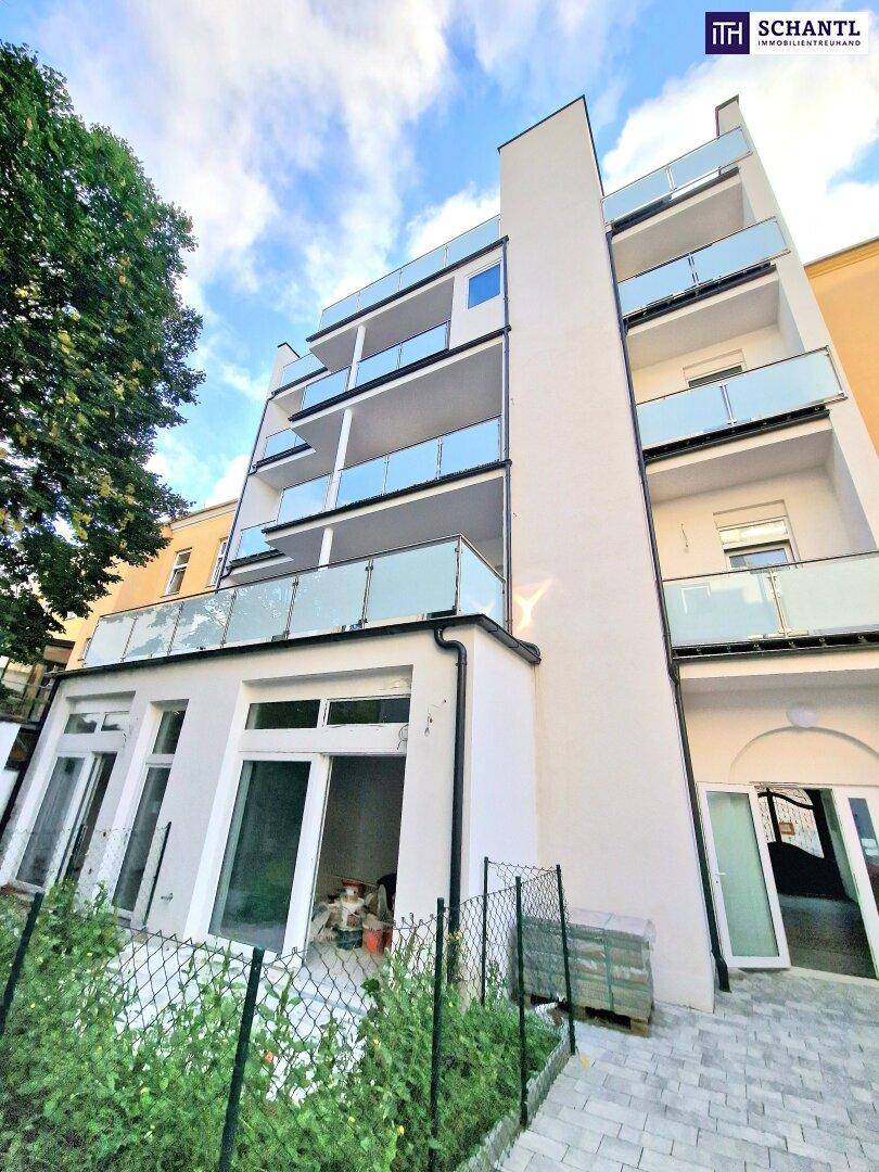 Moderne Gebäudefassade mit mehreren Balkonen und einer im Bau befindlichen Terrasse im Erdgeschoss.