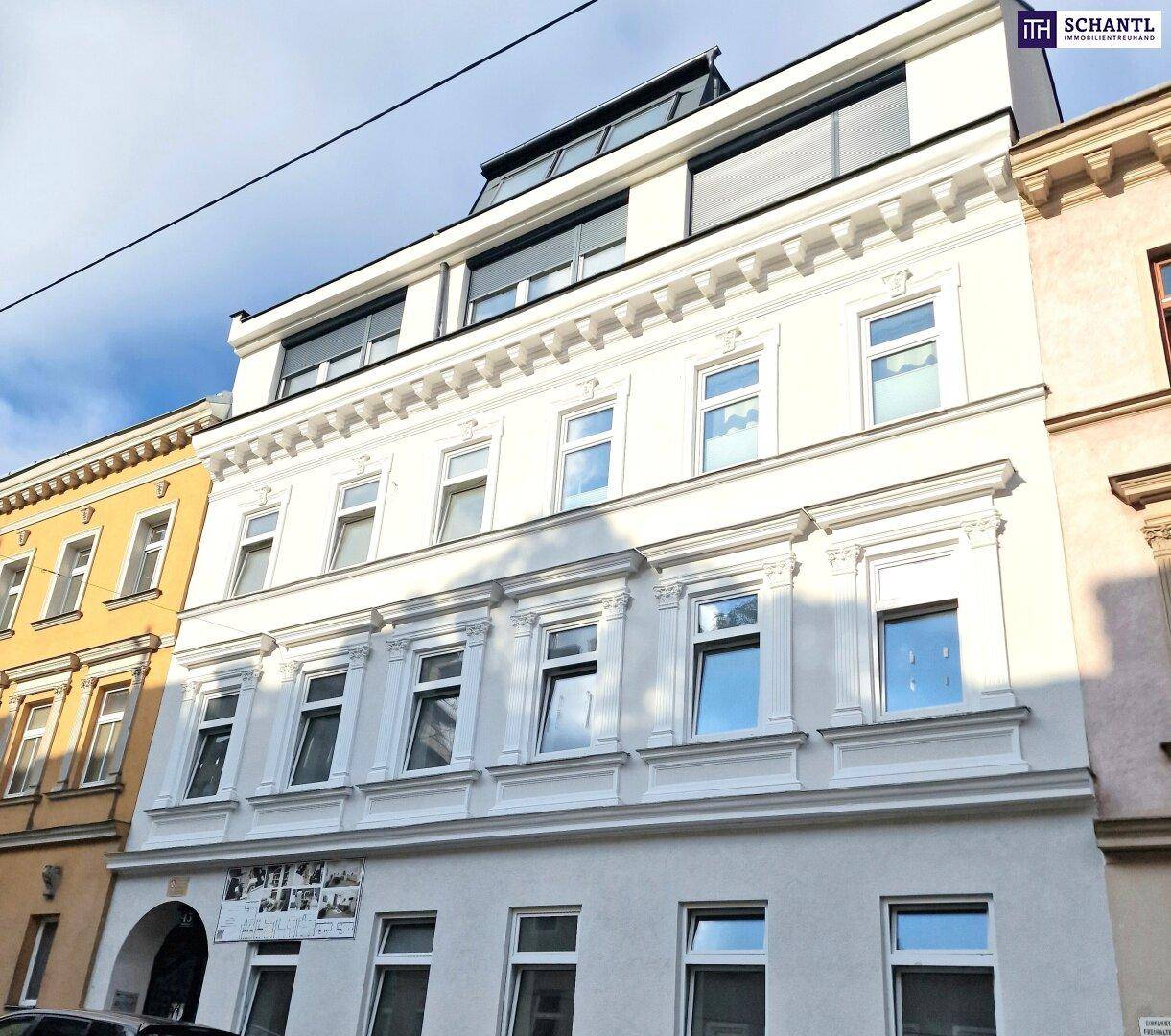 Die frisch renovierte Fassade eines Mehrfamilienhauses mit klassischen Verzierungen und modernen Dachgeschossfenstern.