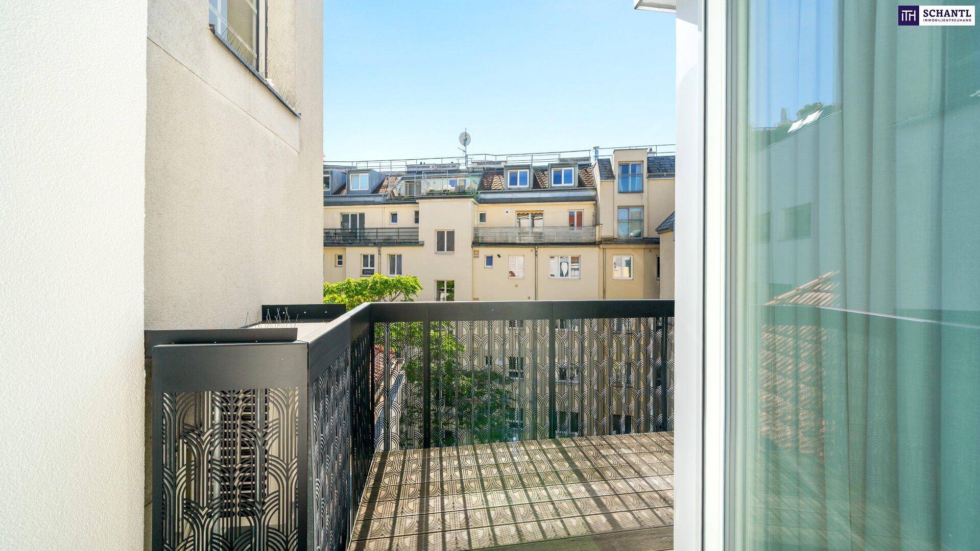 Balkon mit Holzboden und Blick auf die umliegenden Gebäude und einen kleinen Baum.