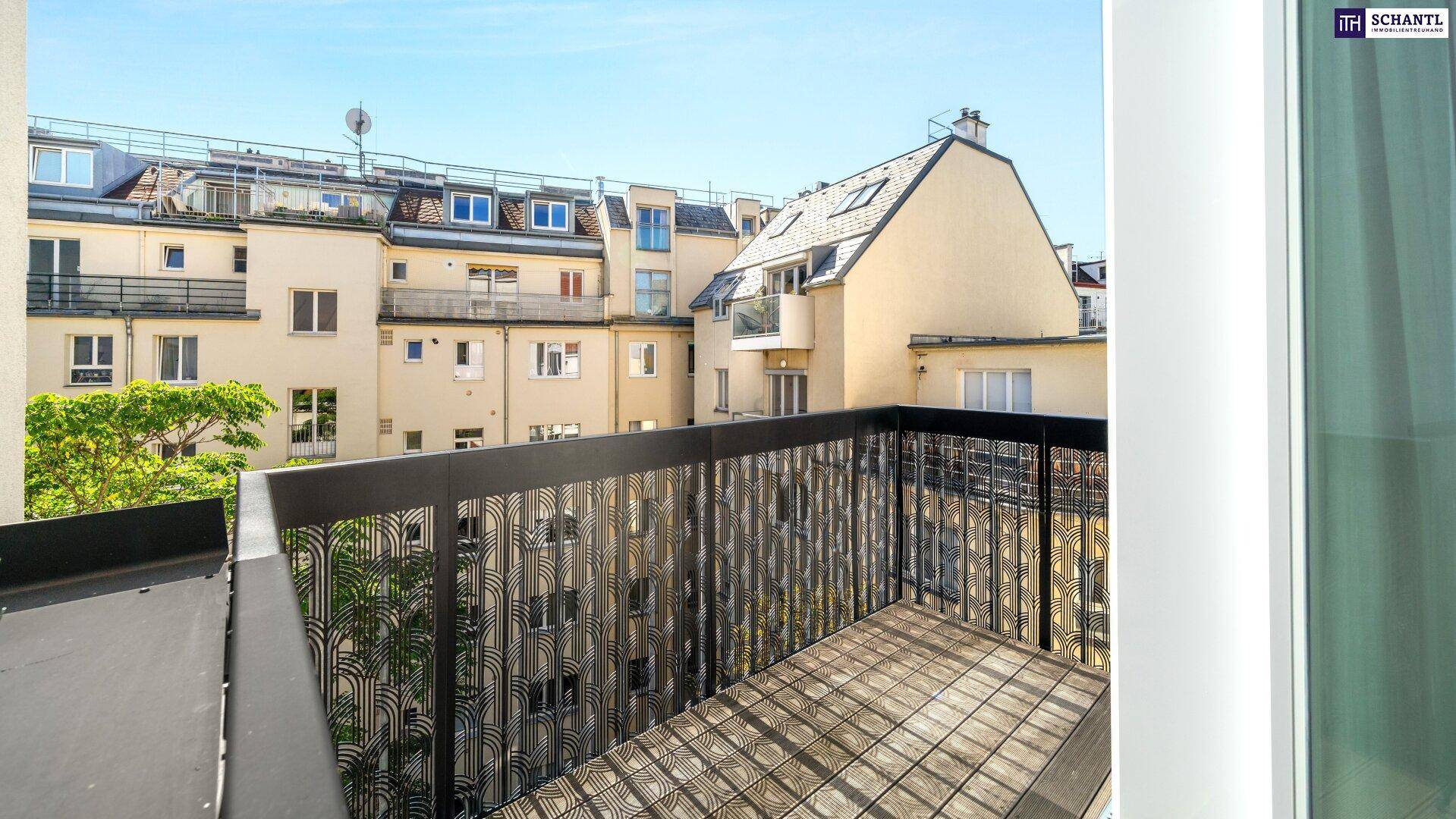 Balkon mit Holzboden und Blick auf die umliegenden Wohngebäude und einen kleinen Baum.