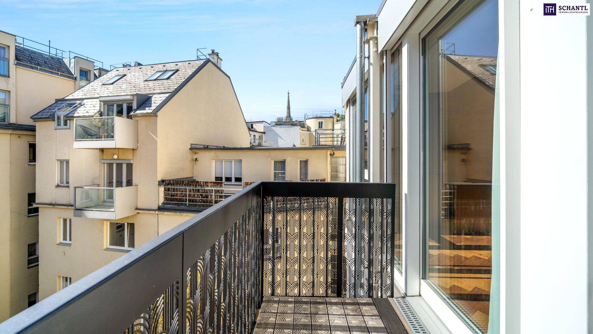 Kleiner Balkon mit Holzboden und Blick auf die umliegenden Gebäude und Dächer.