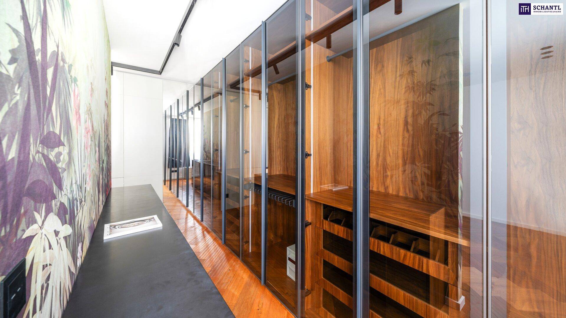 Begehbarer Kleiderschrank mit eleganten Glastüren, Holzregalen und Fischgrätparkettboden.