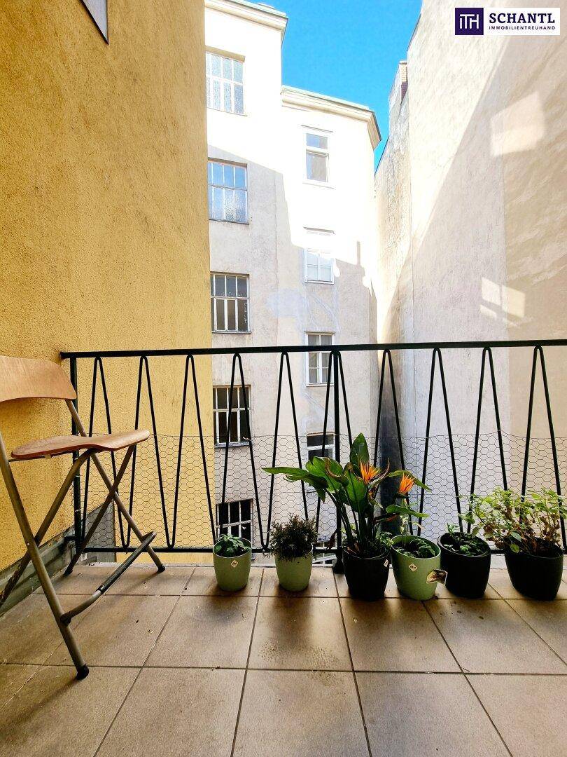 Kleiner Balkon mit Fliesenboden und Blick auf den Innenhof, dekoriert mit Pflanzen.