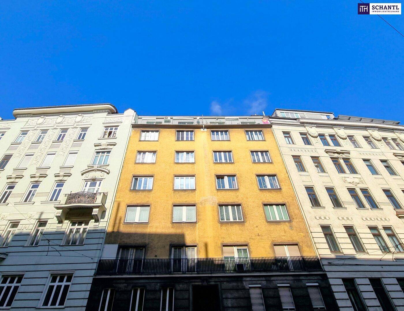 Mehrstöckiges Wohngebäude mit gelber Fassade und vielen Fenstern unter blauem Himmel.