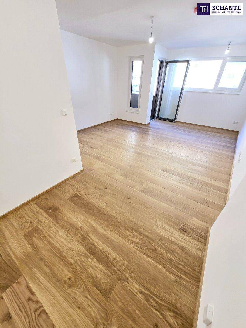 Heller Wohnbereich mit Parkettboden und großen Fenstern, die viel Tageslicht hereinlassen.