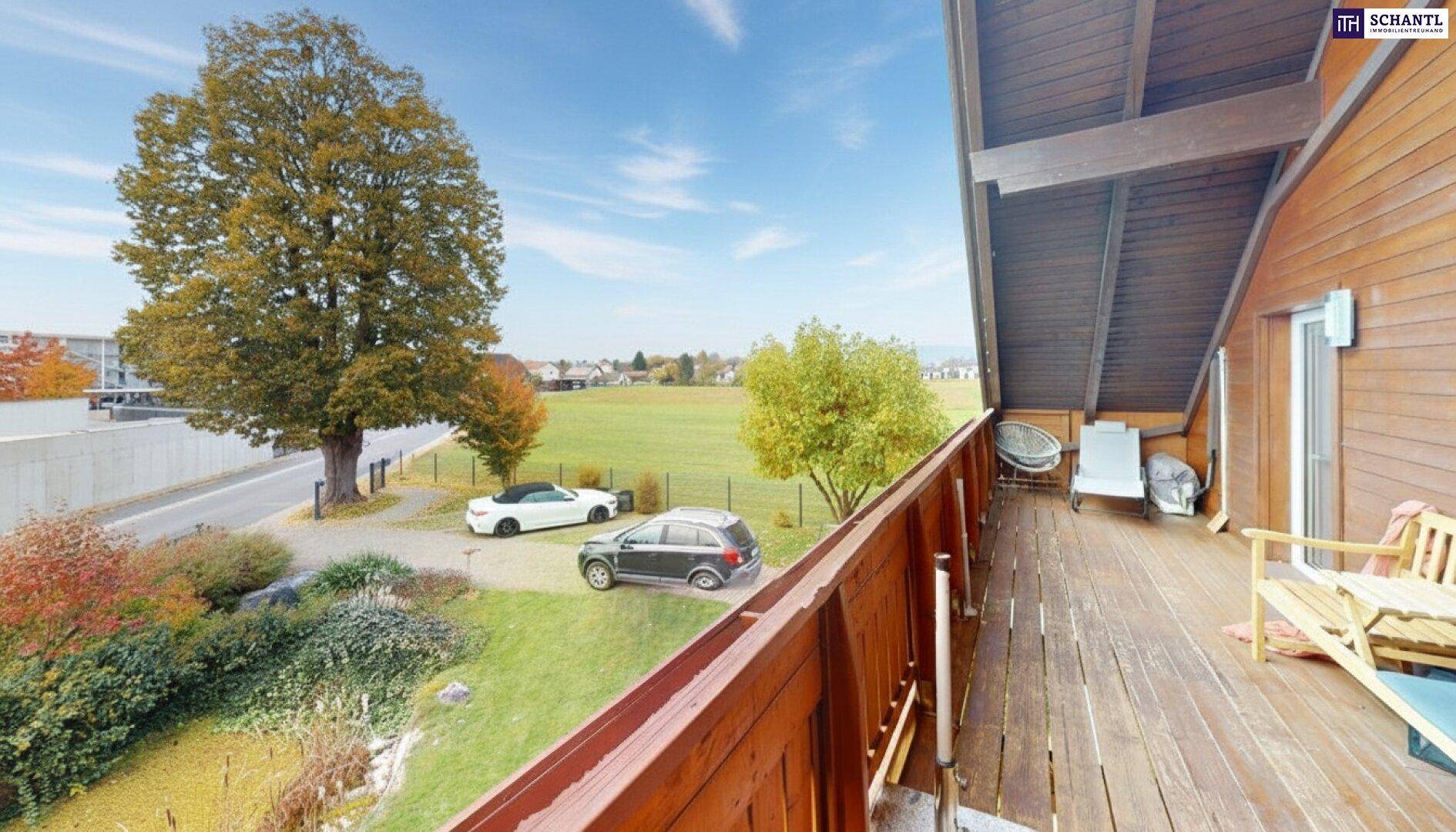 Großer Holzbalkon mit Sitzgelegenheiten und weitem Blick auf die grüne Landschaft.