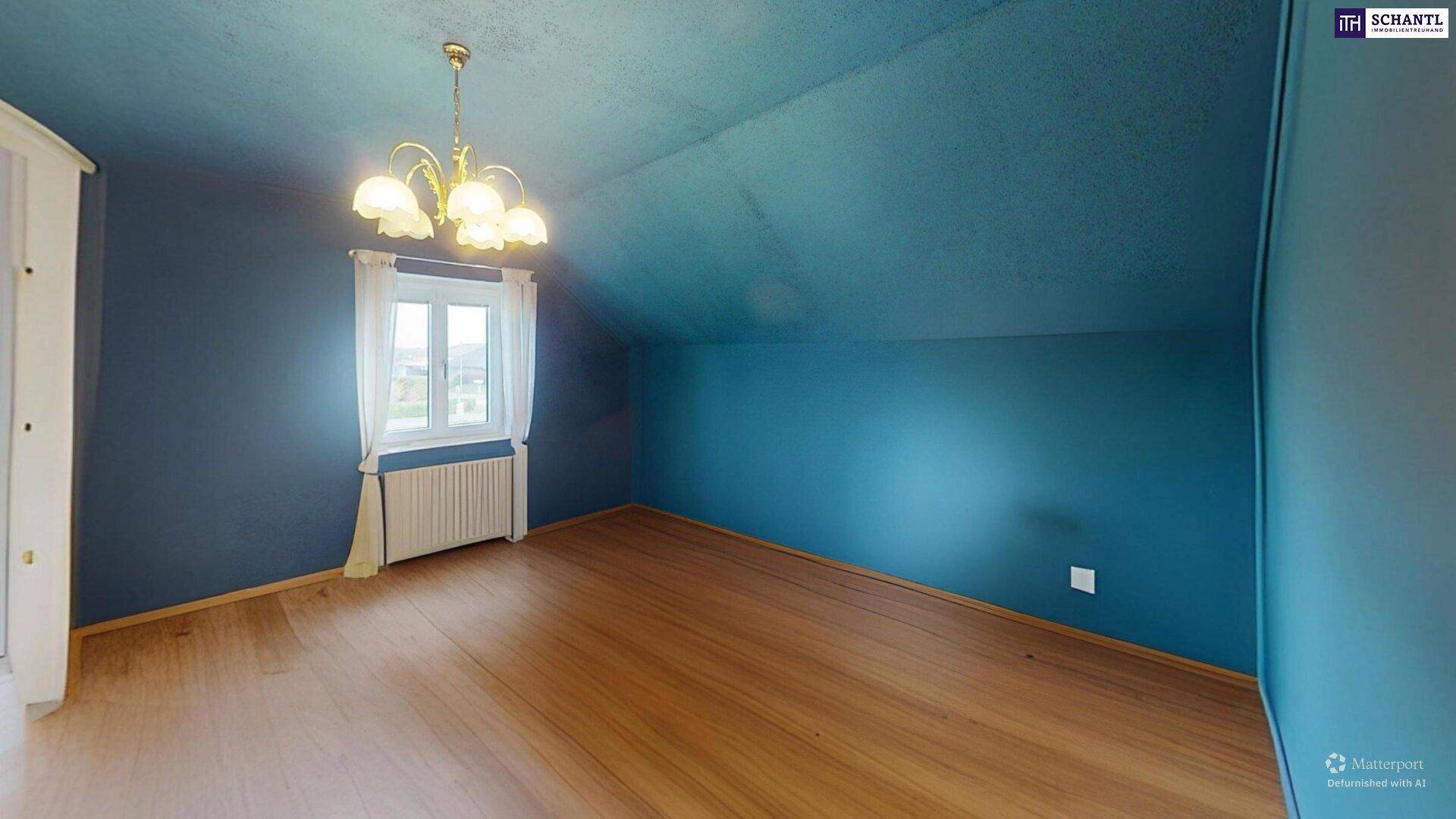 Leeres Schlafzimmer im Dachgeschoss mit blauen Wänden, Holzboden und Fenster.