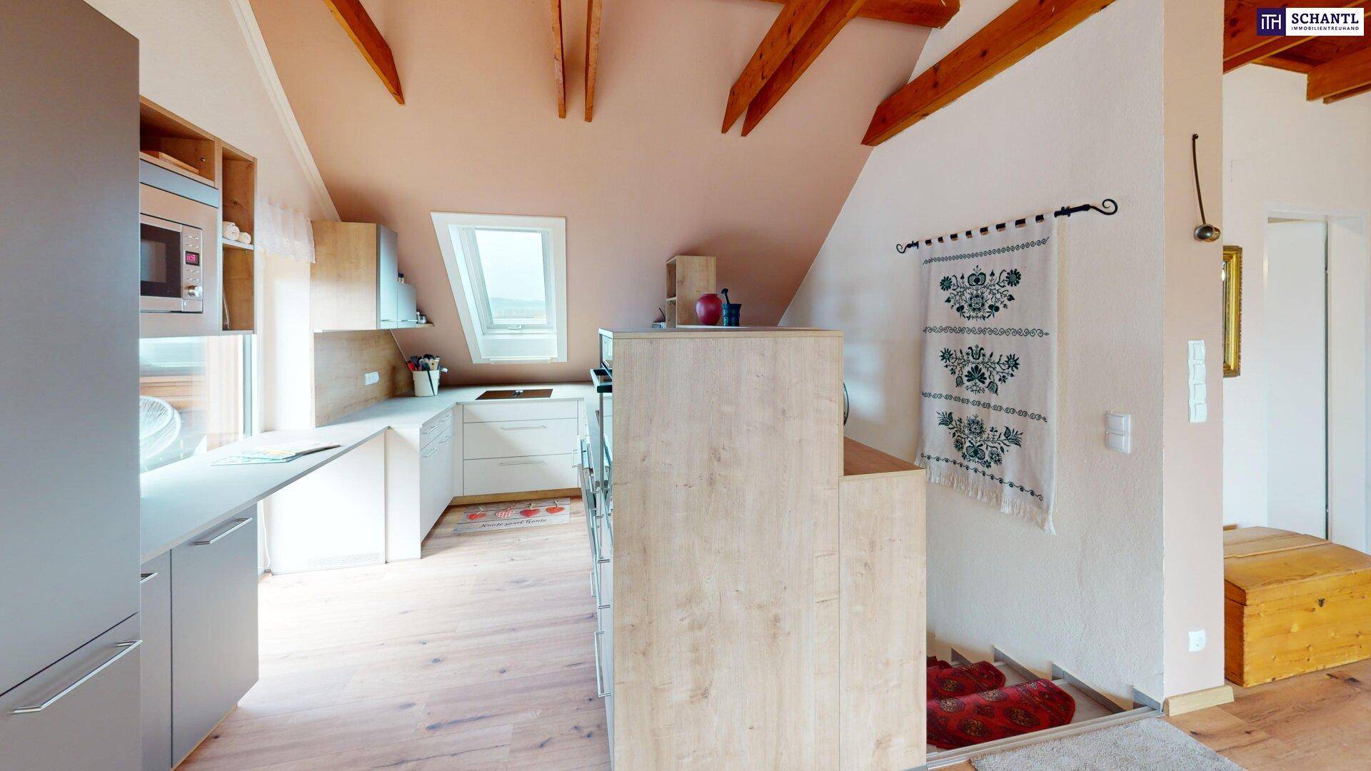 Offene Küche mit Holzbalken, Dachfenster und traditioneller Dekoration.