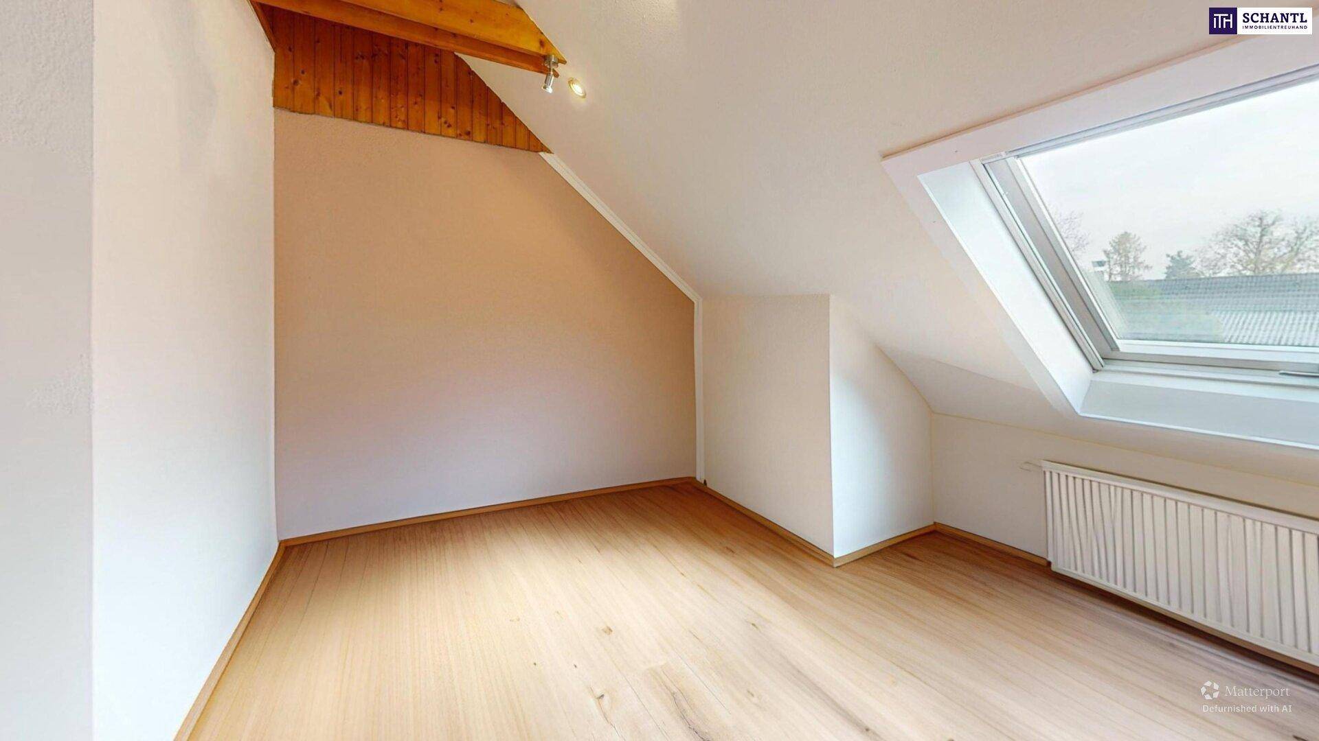 Heller, leerer Raum im Dachgeschoss mit Dachfenster und Laminatboden.