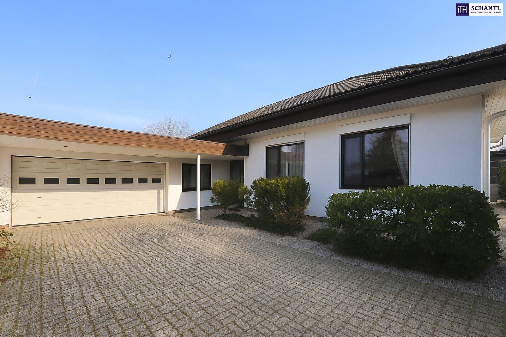 Gepflasterte Auffahrt führt zur Doppelgarage des Hauses mit weißer Fassade.