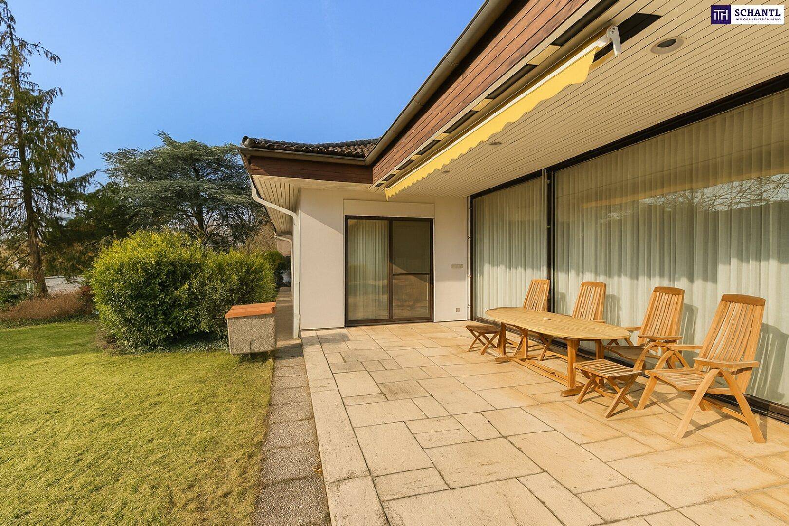 Sonnige Terrasse mit Holzmöbeln, Markise und Zugang zum Garten.