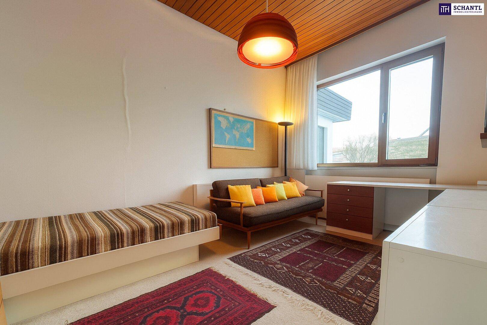 Helles Gästezimmer mit Einzelbett, Schreibtisch und großem Fenster.