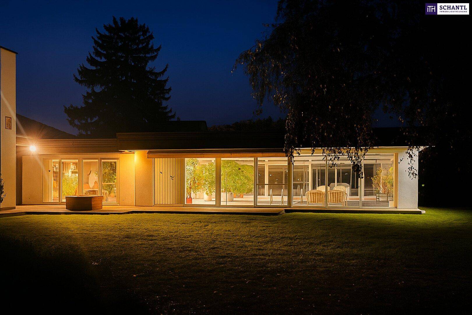 Beleuchtete Außenansicht des Hauses und des Gartens bei Nacht.