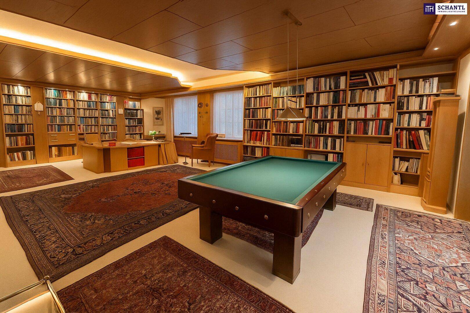 Helles Arbeitszimmer mit Billardtisch, vielen Bücherregalen und indirekter Deckenbeleuchtung.