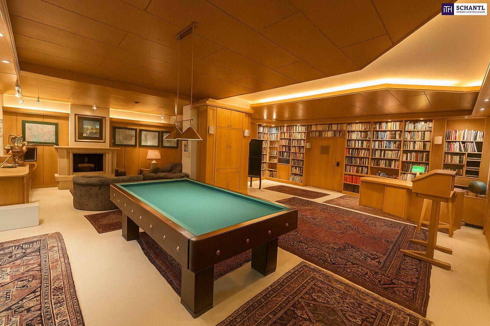 Geräumige Bibliothek mit Billardtisch, Kamin und vielen Bücherregalen aus Holz.